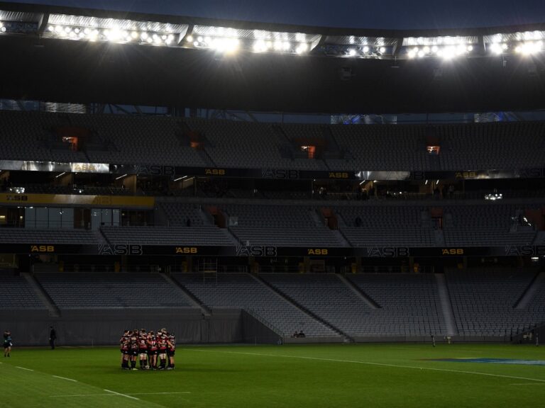 Photo of a rugby team huddled up in a stadium