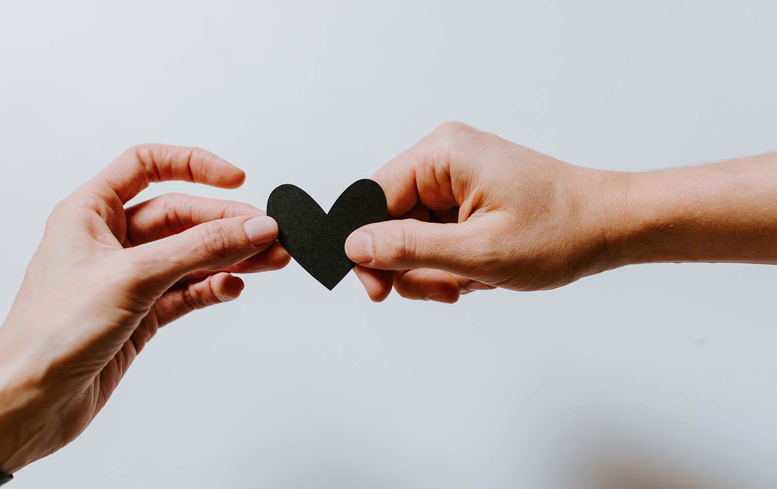 One hand passing a heart to another hand. Illustrating the idea of caring.