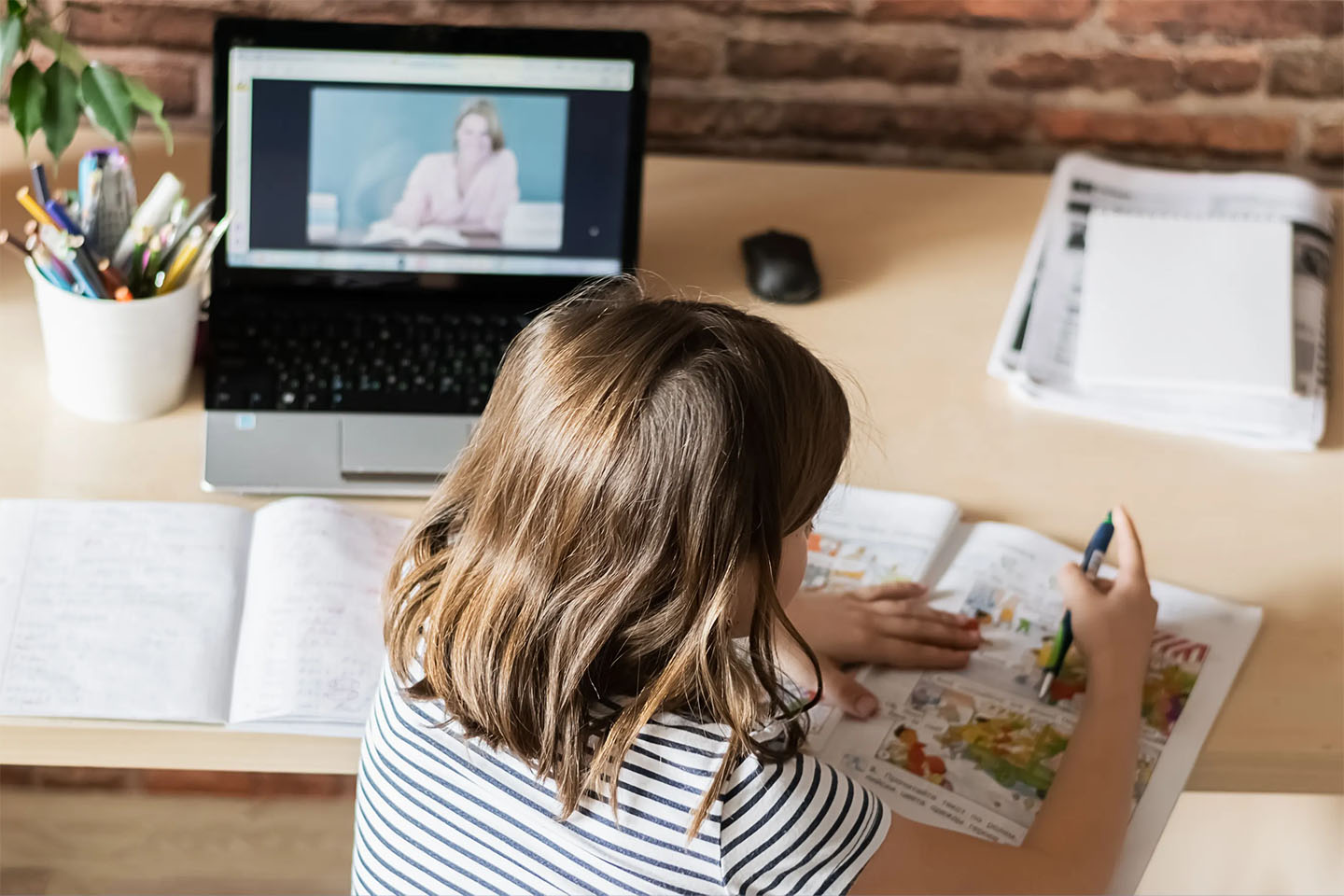 The concept of distance online learning self-isolation. Child sitting home desk doing lessons through a digital laptop.