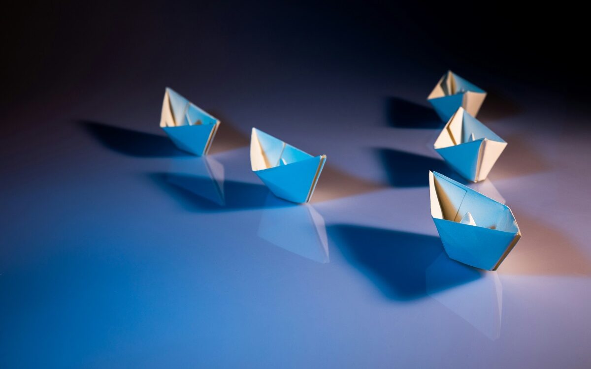 ©KOBU Agency / Unsplash Five paper boats in a v formation, following one at the front