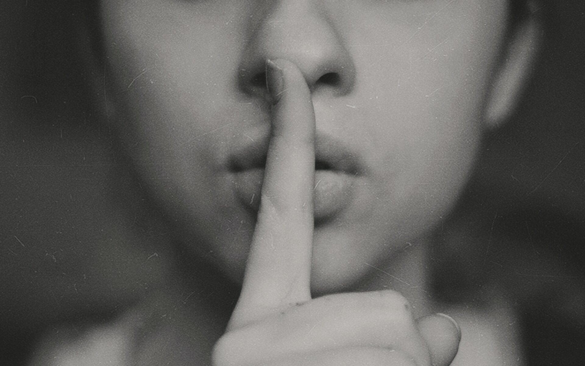 ©Kristina Flour/Unsplash Photo of a woman with her finger to her lips making the sign to be quiet.