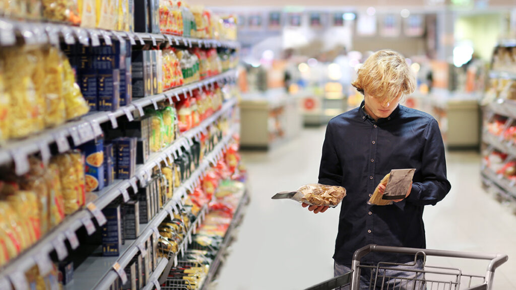 Man shopping in supermarket, reading product information