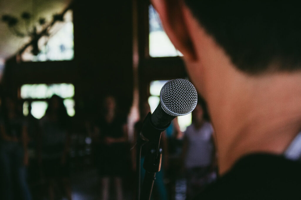 Man standing in front of microphone, © Marcos Luiz Photograph / Unsplash