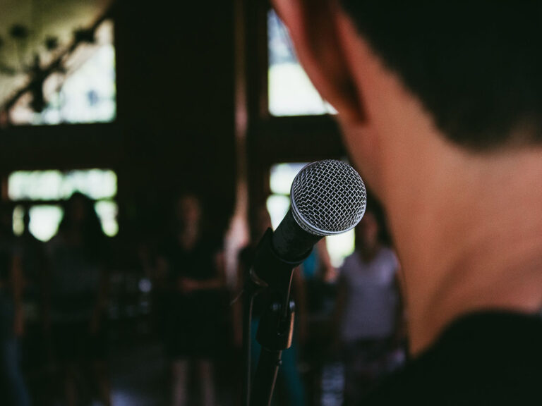 Man standing in front of microphone, © Marcos Luiz Photograph / Unsplash