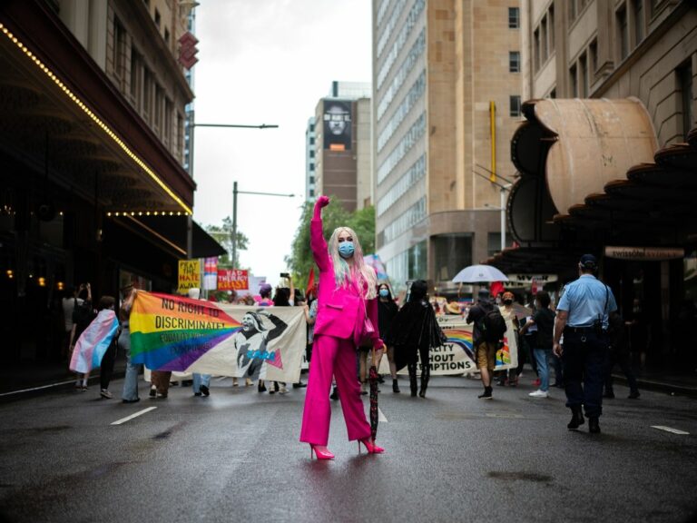 A photo of an LGBT+ activist holding their fist up at a protest representing leadership as a member of the LGBT+ community