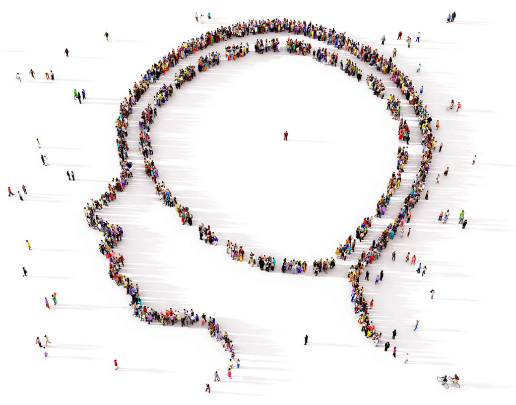 A large and diverse group of people seen from above gathered together in the shape of a symbol of the human mind