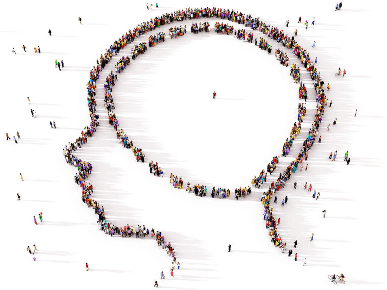 A large and diverse group of people seen from above gathered together in the shape of a symbol of the human mind