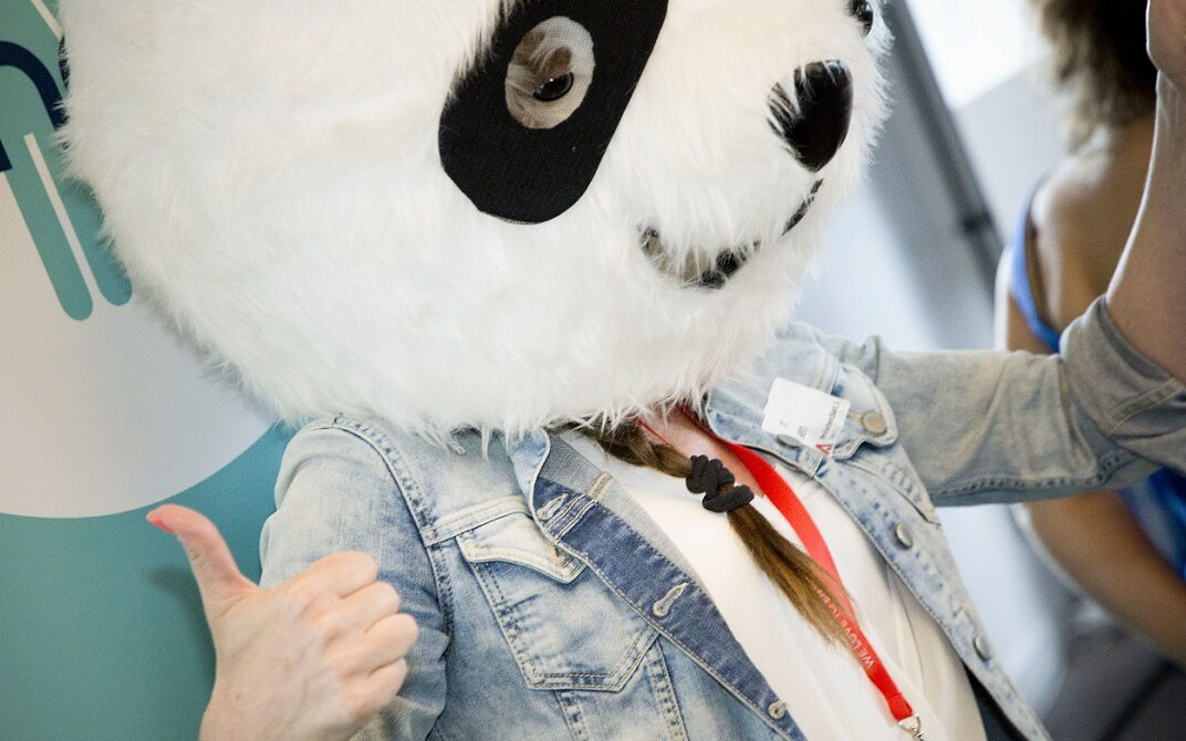 ©Gabriele di Stefano Photo of a woman with a braid wearing a costume Panda head, showing a thumbs up, at a PANDA Network event.