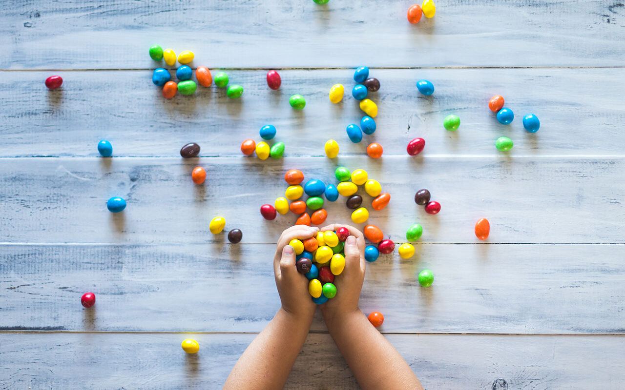 © Patrick Fore / Unsplash Selective photo of kid holding candies on gray wooden pallet board, © Patrick Fore / Unsplash