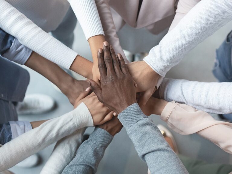 Photo of a group of diverse colleagues putting their hands together.