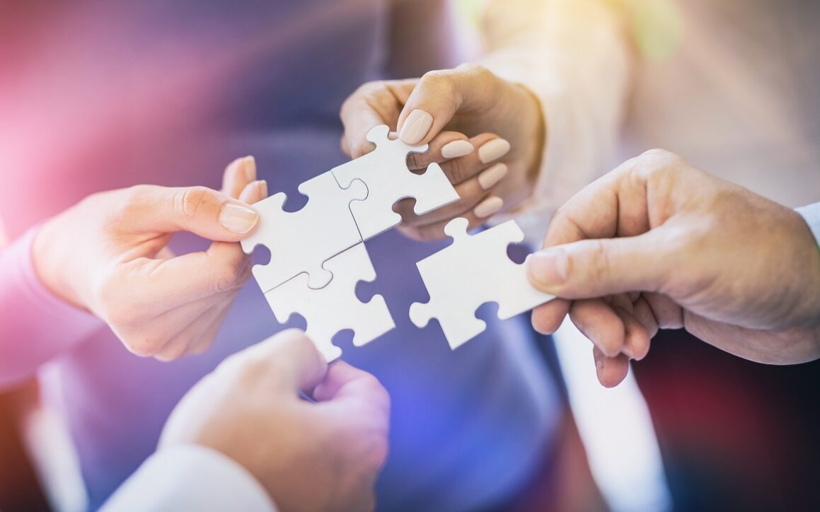 A group of business people assembling jigsaw puzzle. The concept of cooperation, teamwork, help and support in business.