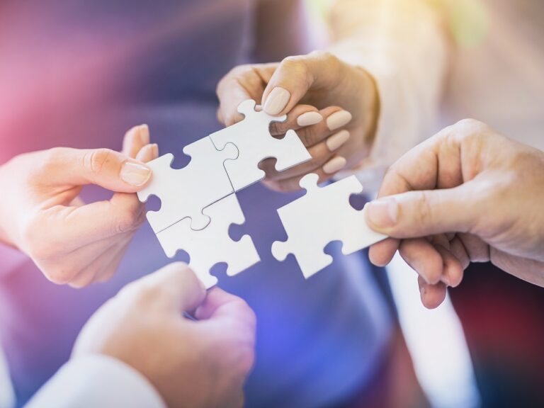 A group of business people assembling jigsaw puzzle. The concept of cooperation, teamwork, help and support in business.