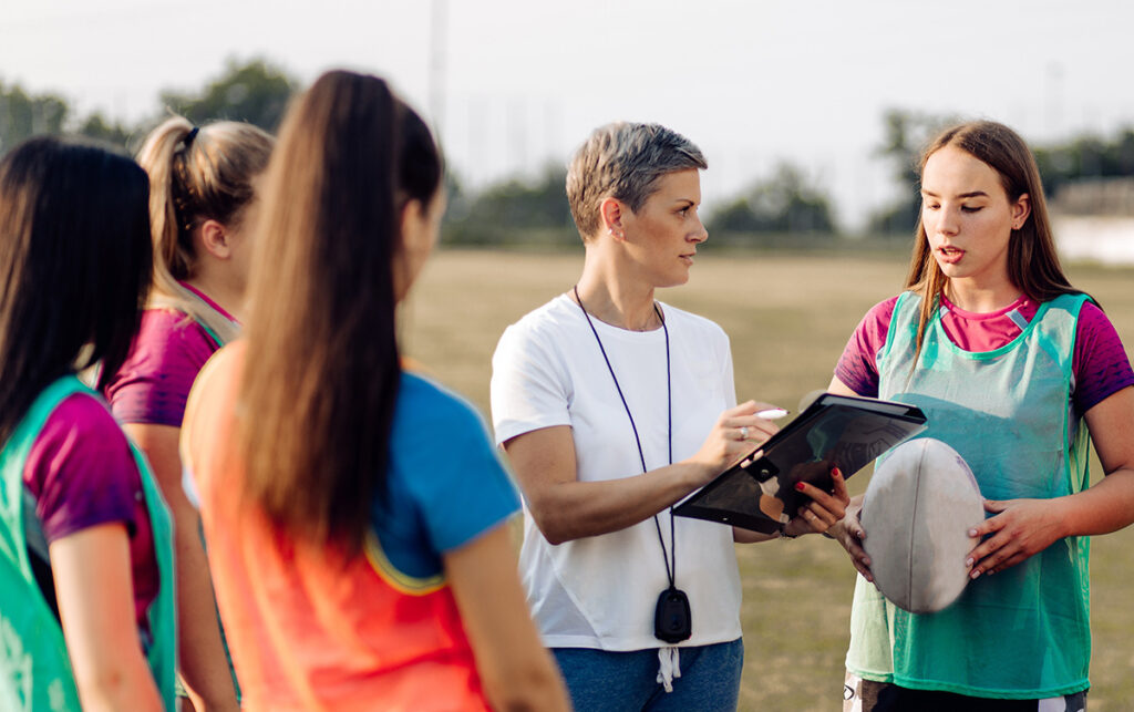 Female rugby coach talking to her players.