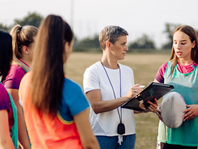 Female rugby coach talking to her players.