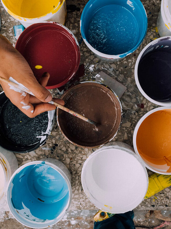 ©Russn/Unsplash Photo of someone painting with many pots of paints.