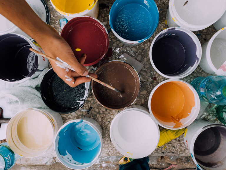 Photo of someone painting with many pots of paints.