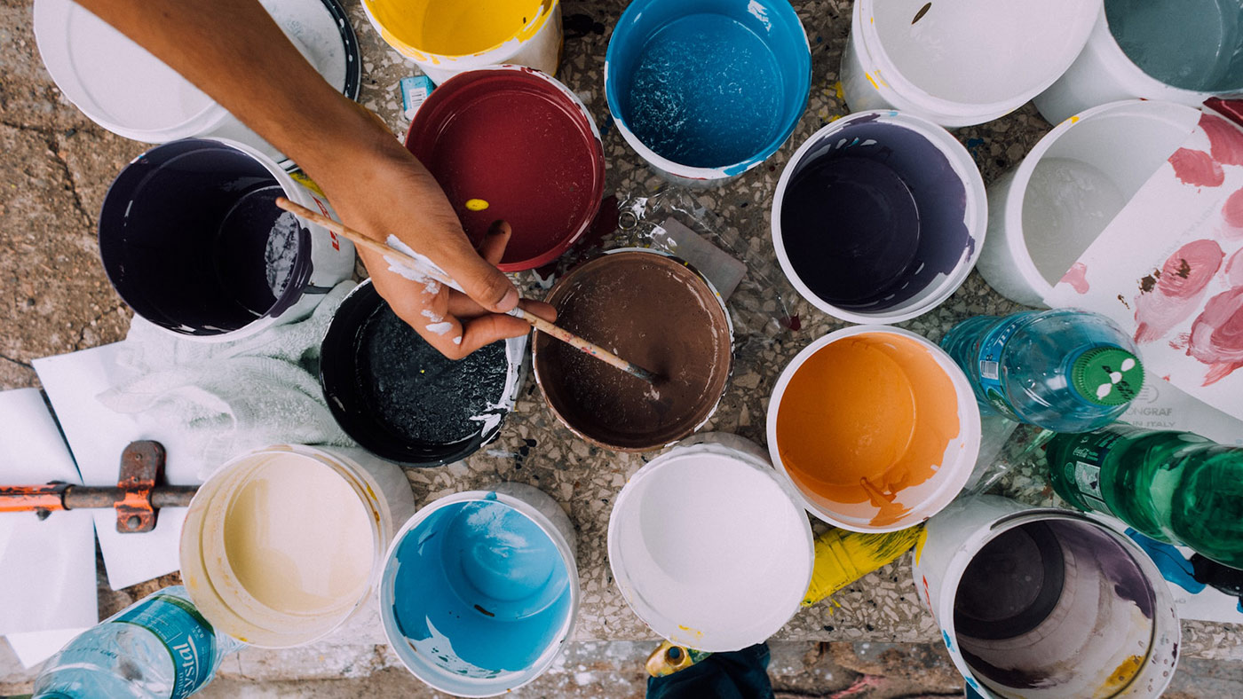 Photo of someone painting with many pots of paints.