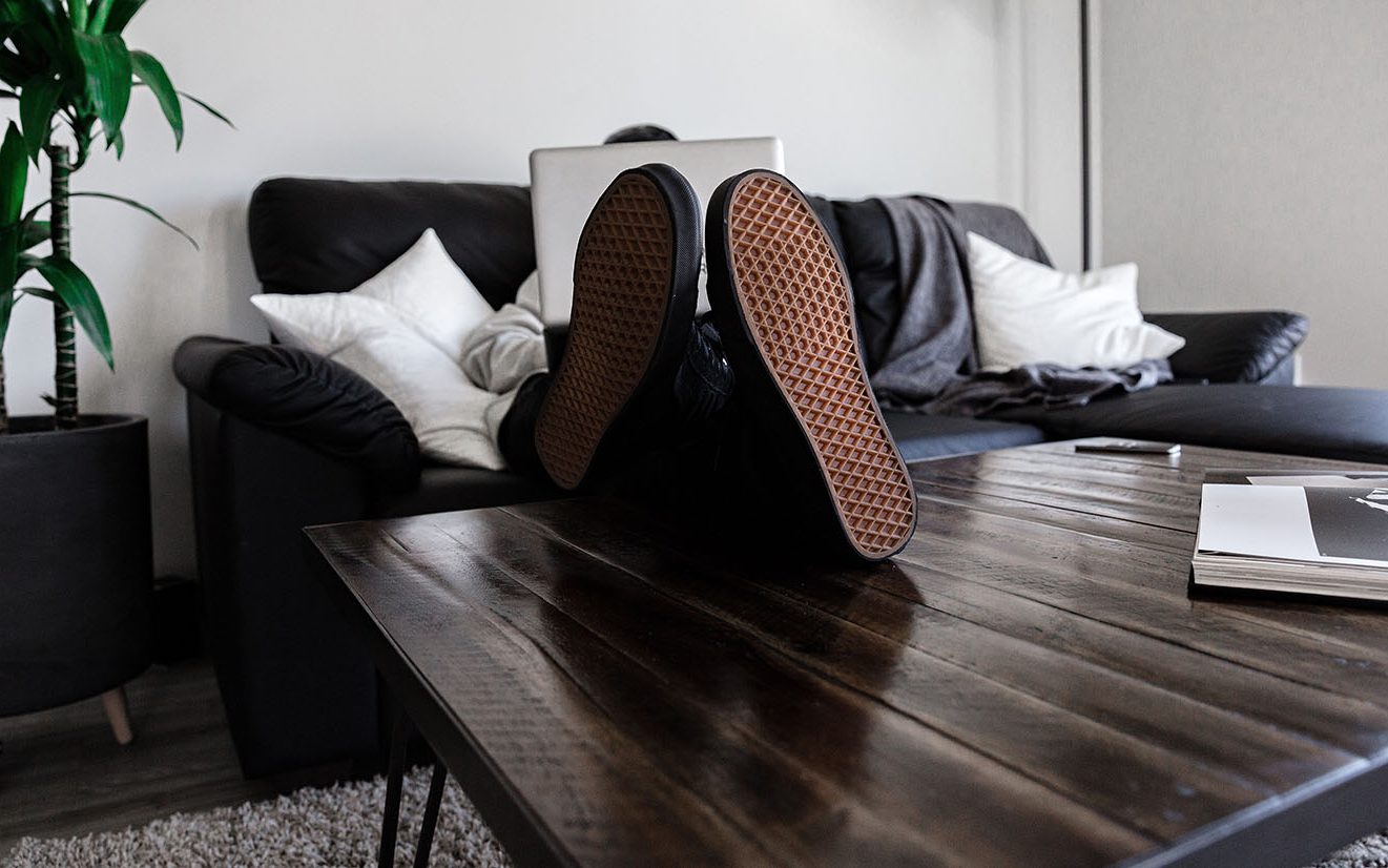 Photo-Credit-Dillon-Shook-Unsplash Man on a couh, shoes ontable works