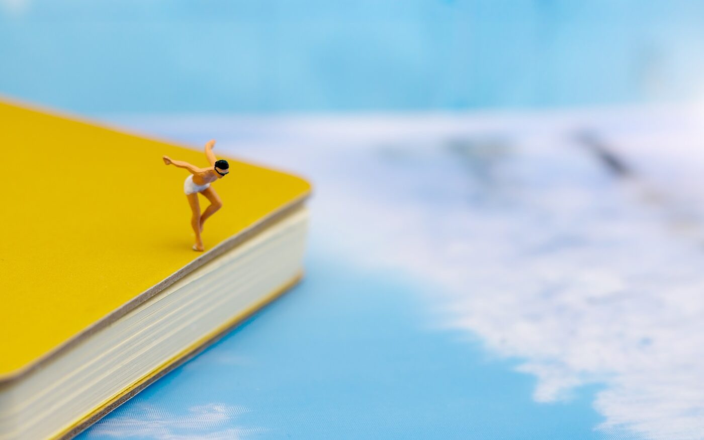 ©Rattana.R/Shutterstock Photo of a male figurine wearing a bathing suit about to dive of a book in to a pretend ocean.