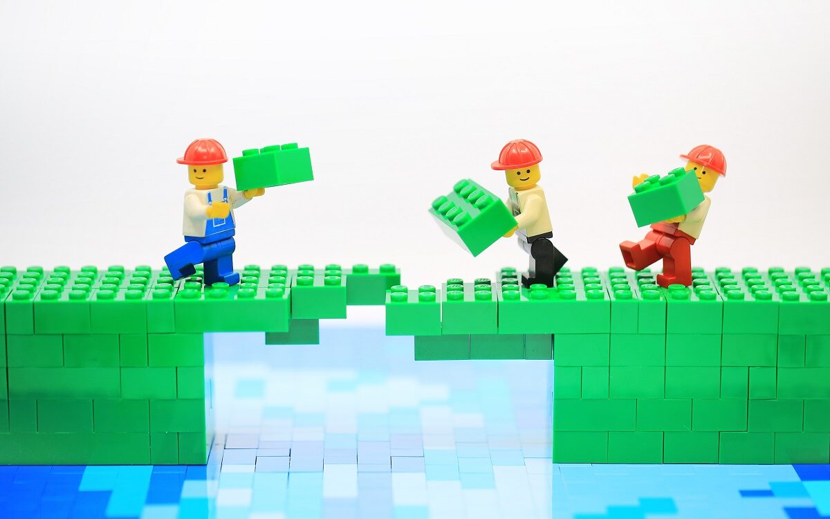 ©Lewis Tse / Shutterstock Lego figures are working together to build a bridge out of legos