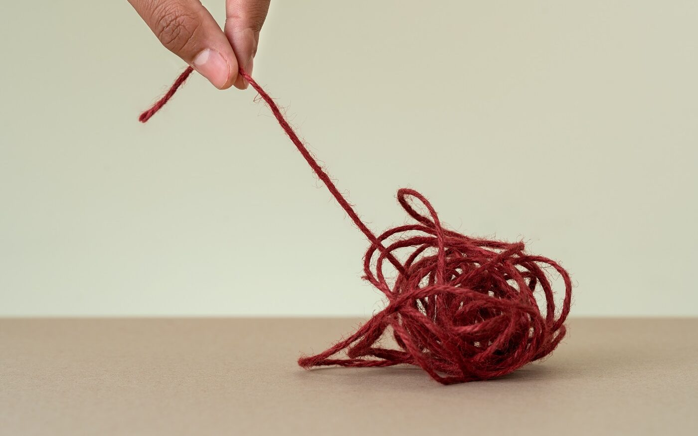 © Shutterstock Close up photo of a hand pulling the end of a red ball of string.
