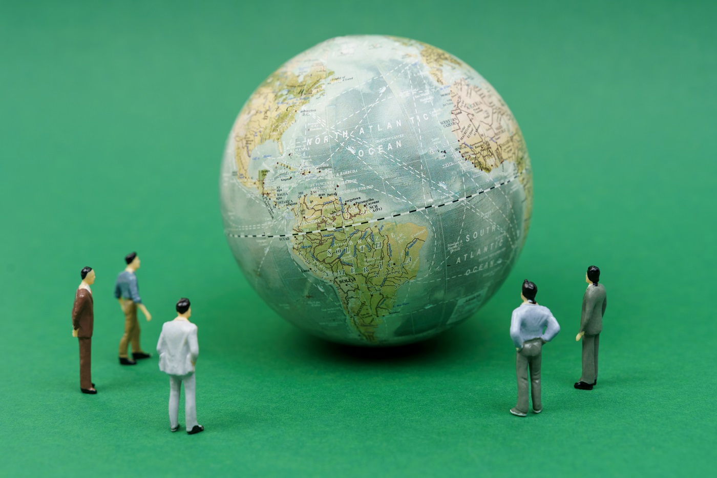 Image of five male figurines looking at a globe.