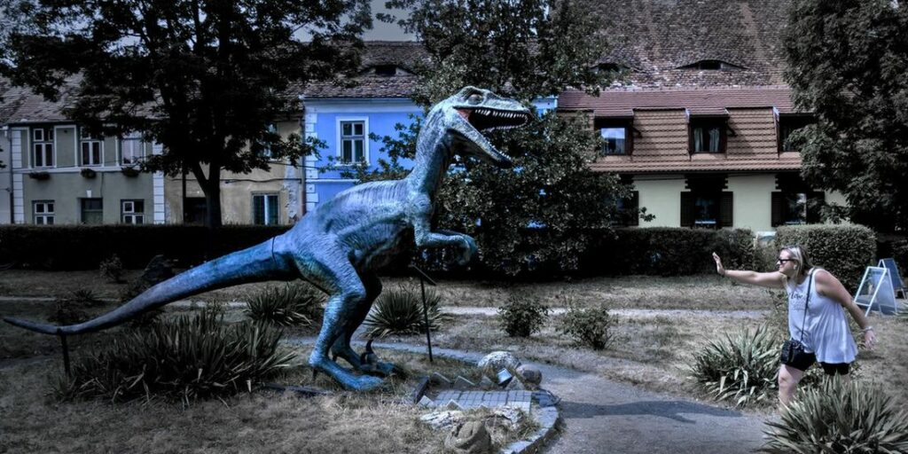woman holding off a velociraptor statue