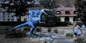 woman holding off a velociraptor statue