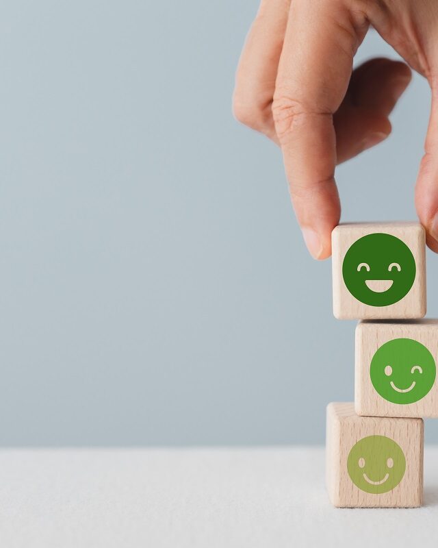 ©Ratana21 / Shutterstock A stack of 3 wooden blocks with happy faces on them that get progressively deeper green and happier as they move up the stack