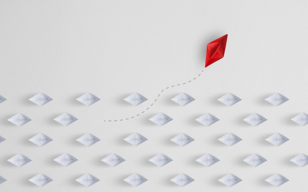 Image of a paper boat sailing away from the group of paper boats