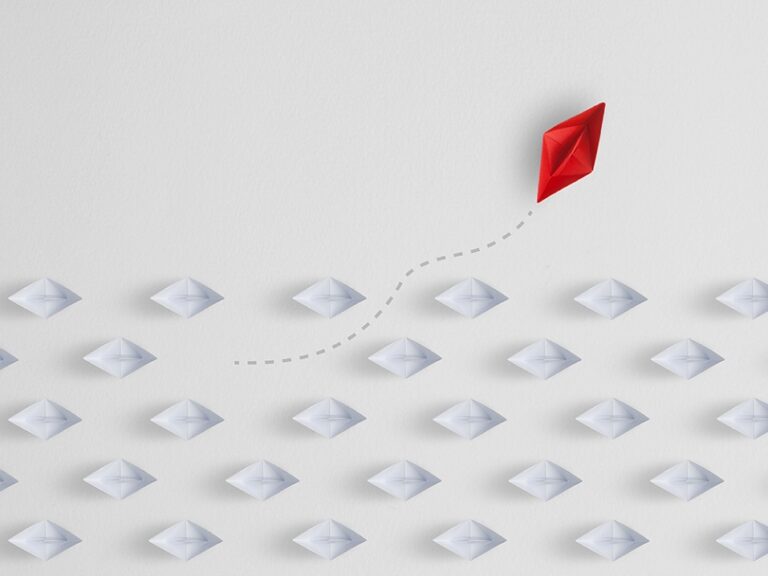 Image of a paper boat sailing away from the group of paper boats