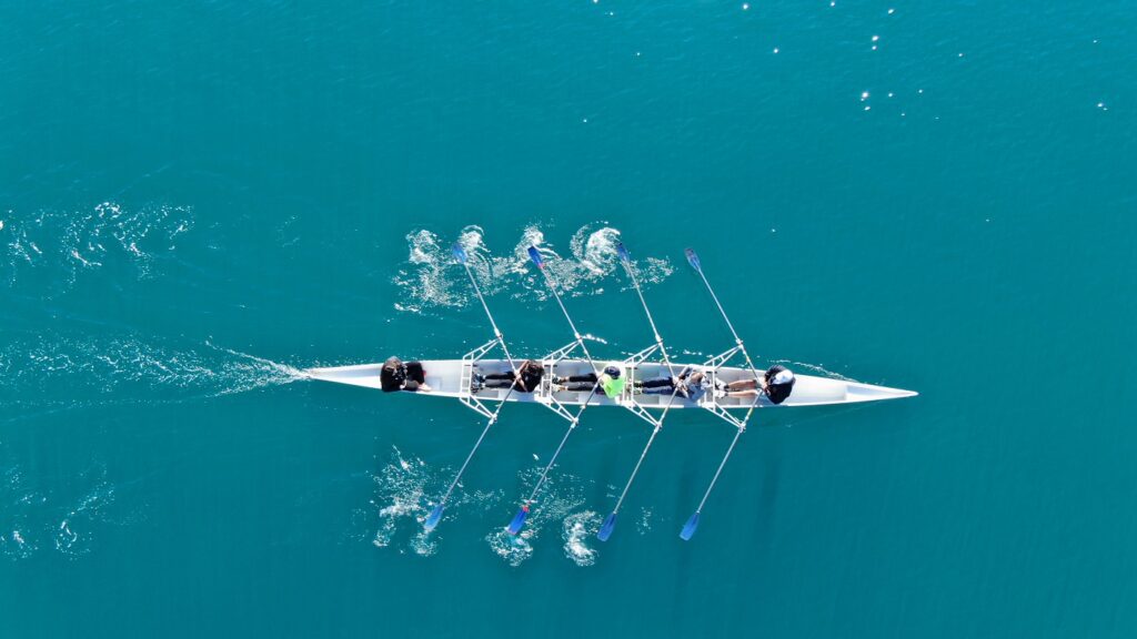 Photo of a rowing team rowing on the water.