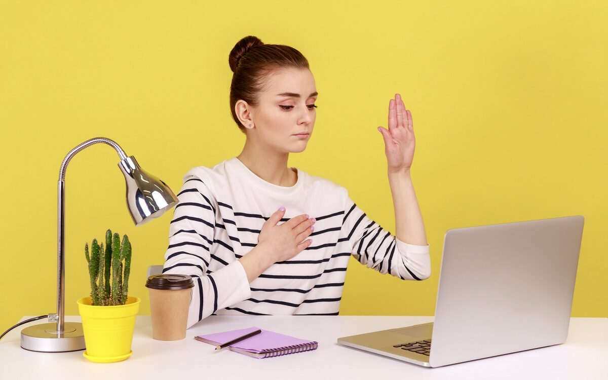 ©Khosro/Shutterstock woman raising her hand to make a promess to her colleagues at a distance