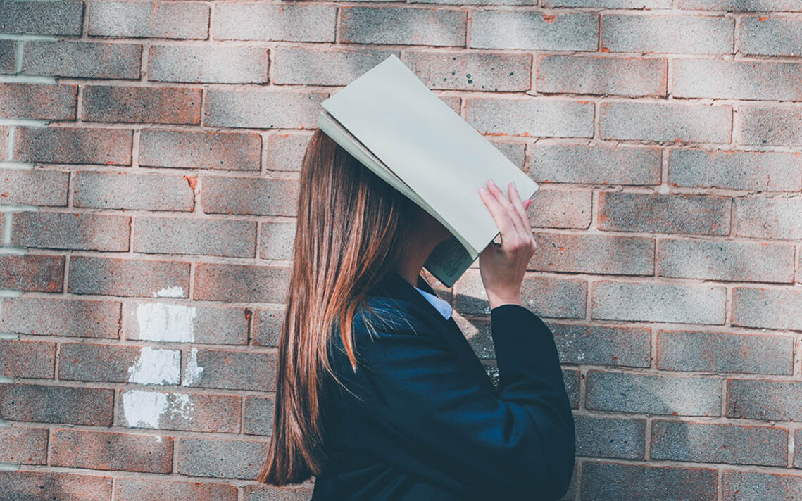 © Siora Photography / Unsplash Woman covering her face with an open book, © Siora Photography / Unsplash