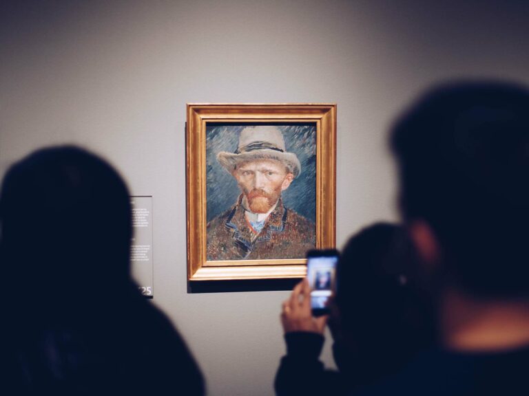 Photo of someone taking a picture of a Vincent VanGogh portrait in a museum.