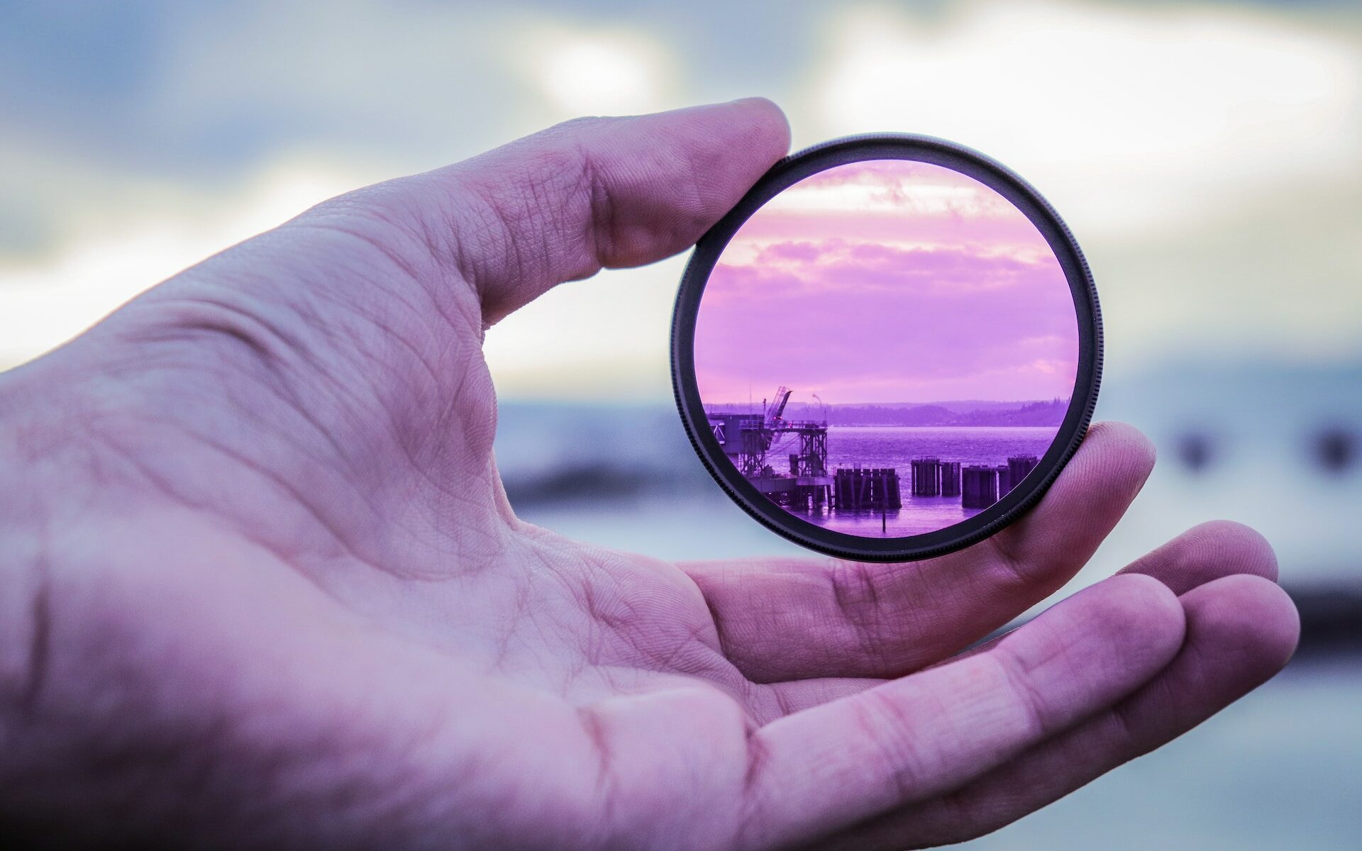 ©Stephen Kraakmo/Unsplash Close up photo of a hand holding a lens that is magnifying the background