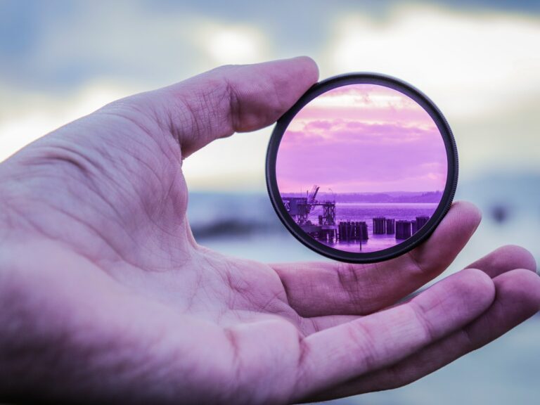 Close up photo of a hand holding a lens that is magnifying the background