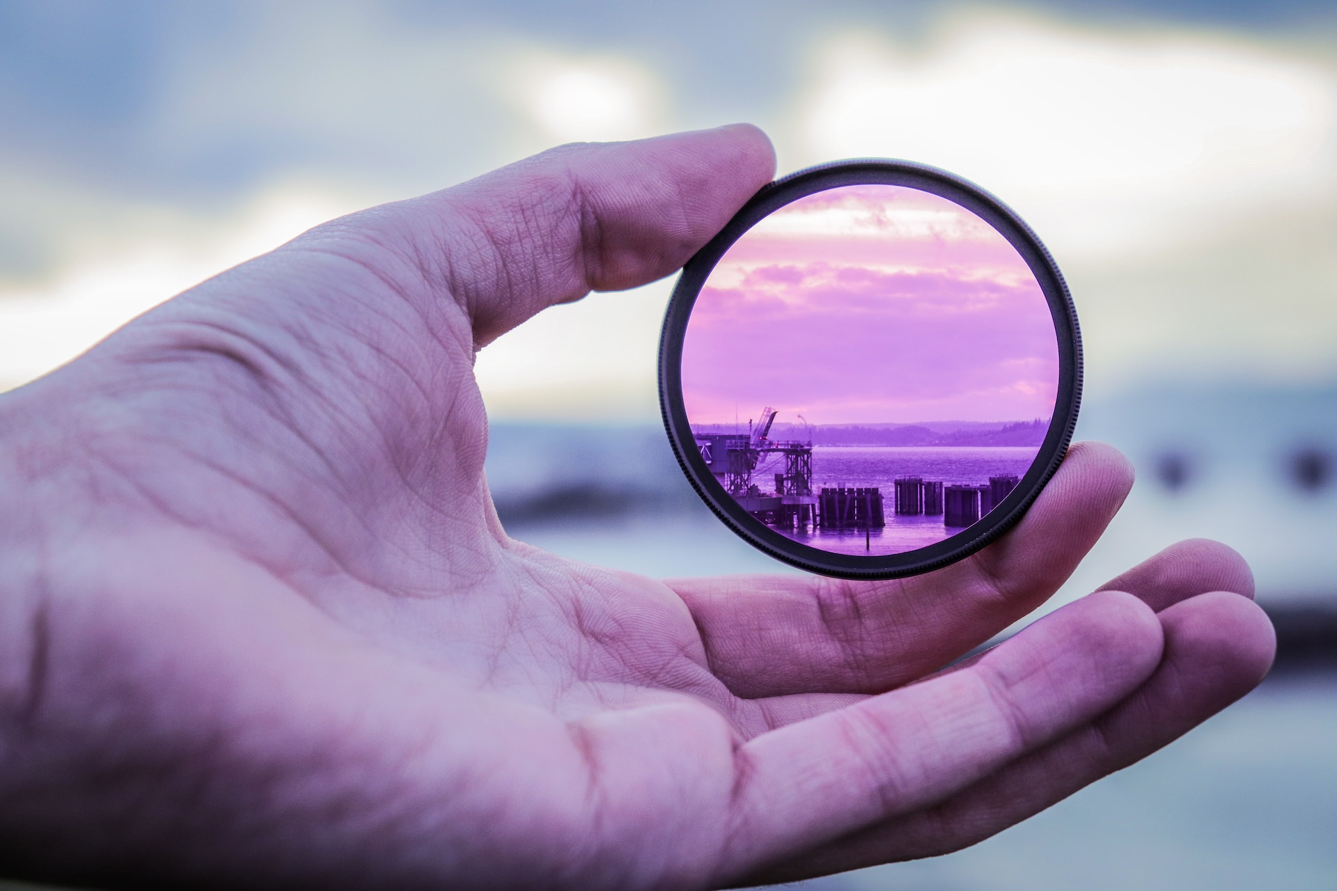 Close up photo of a hand holding a lens that is magnifying the background
