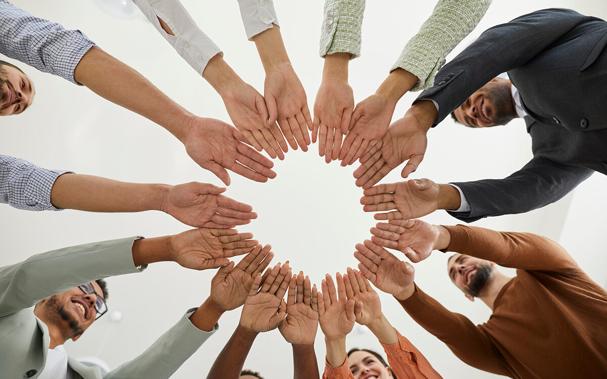 Studio-Romantic-AdobeStock Group of happy diverse people joining hands in a circle.