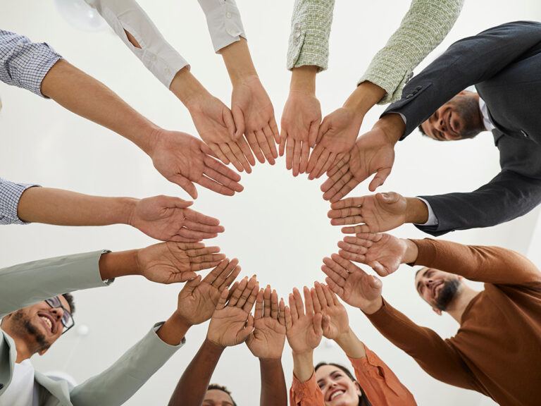 Group of happy diverse people joining hands in a circle.