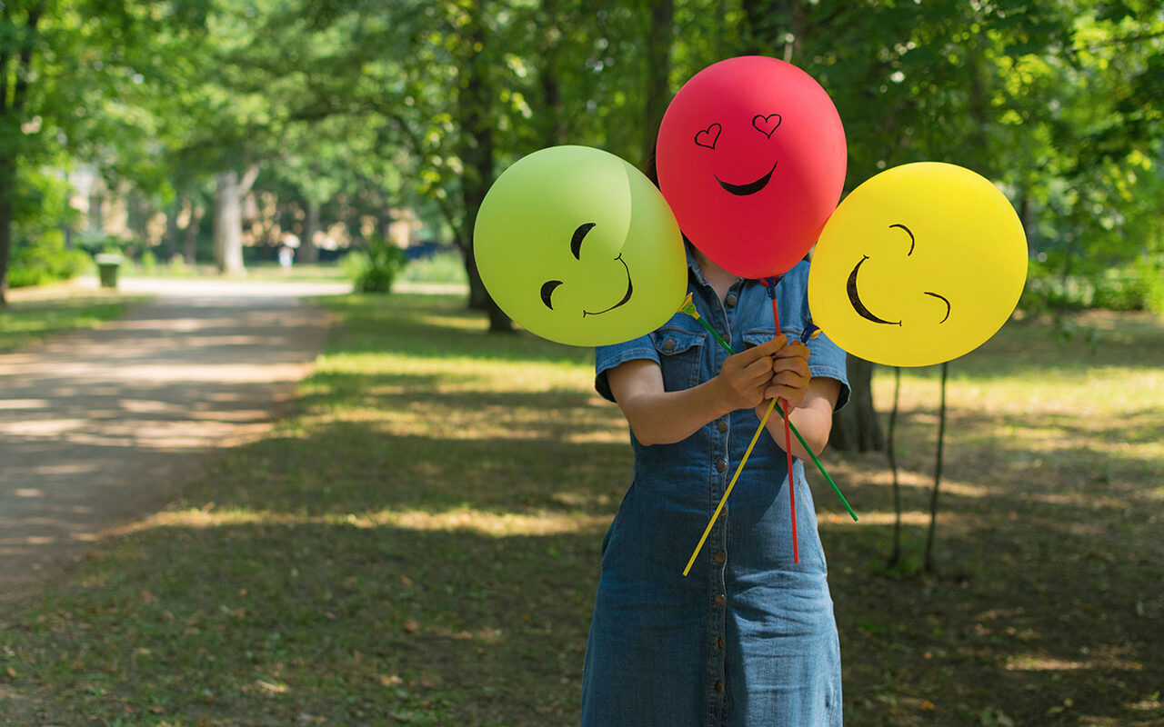 © Tatiana / Adobe Stock Woman holding air balloons with funny drawn faces, ,© Tatiana / Adobe Stock