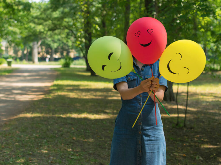 Woman holding air balloons with funny drawn faces, ,© Tatiana / Adobe Stock