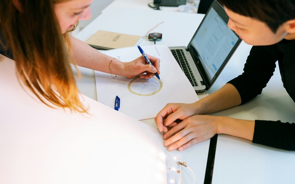 ©This is Engineering / Unsplash Two people lean over a drawing working on an idea together