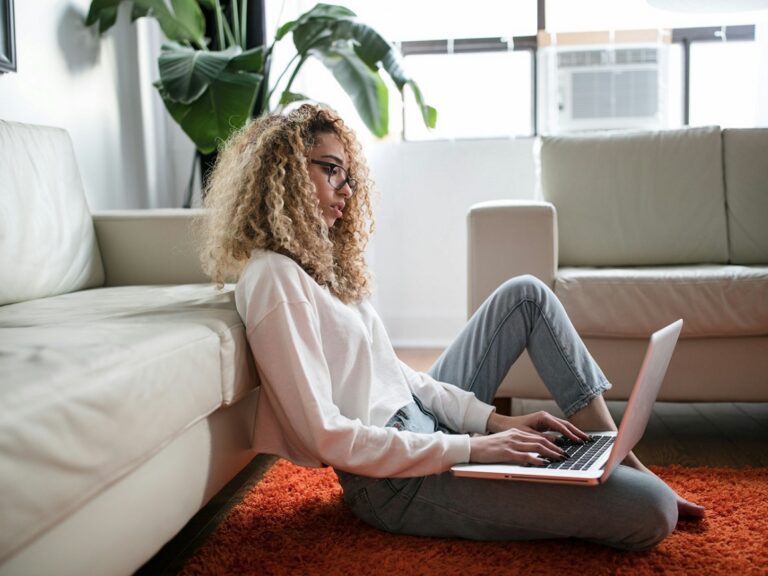 Photo of a woman sitting in her living room and working on her computer
