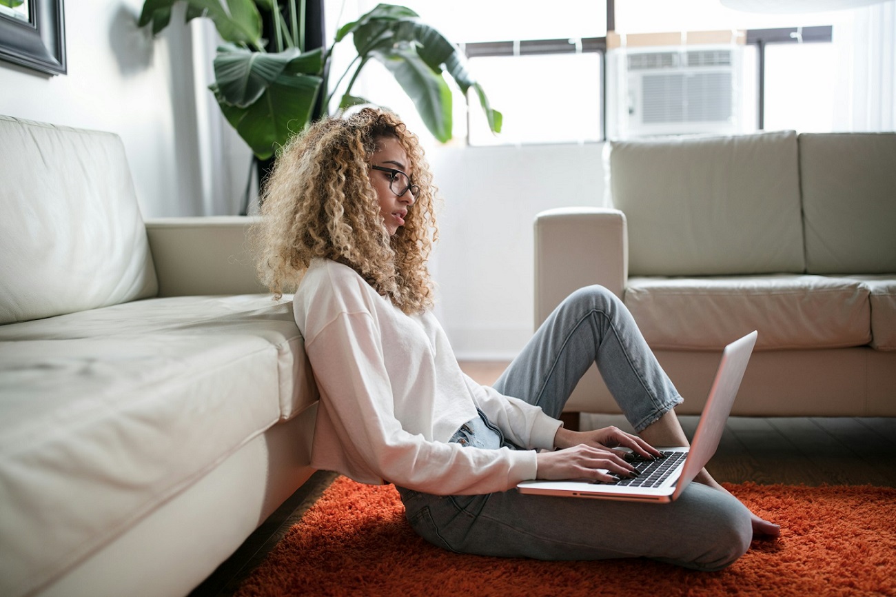 Photo of a woman sitting in her living room and working on her computer