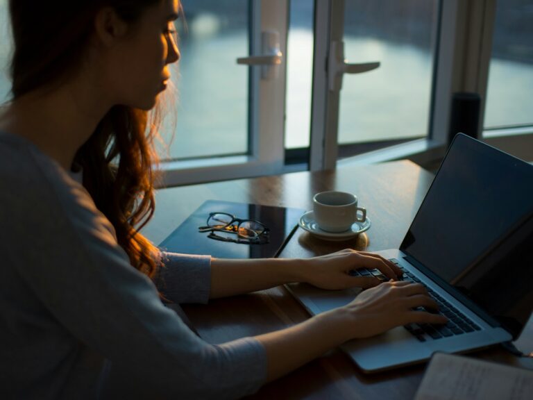 A woman sits at her desk, typing on her computer