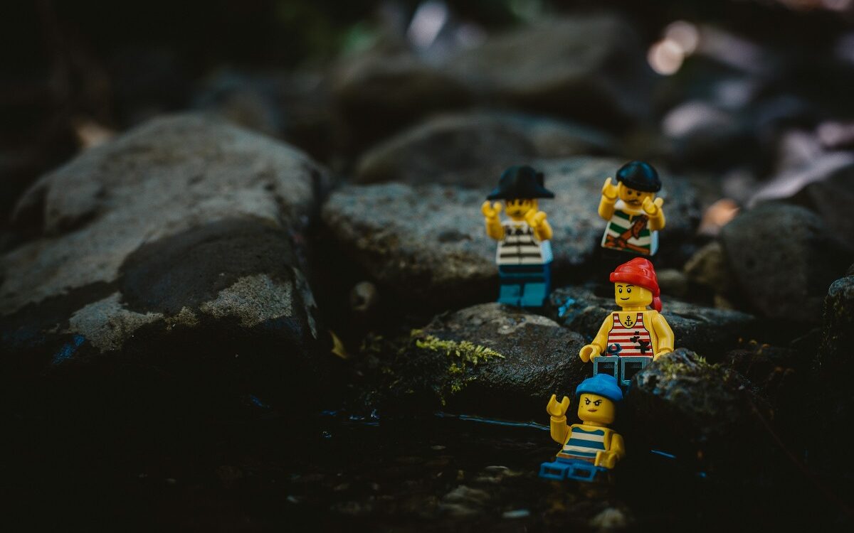 ©Tom Briskey / Unsplash Lego characters dressed as pirates are navigating a rocky landscape