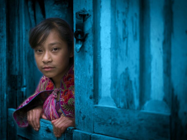 Young poor girl looking out of a window
