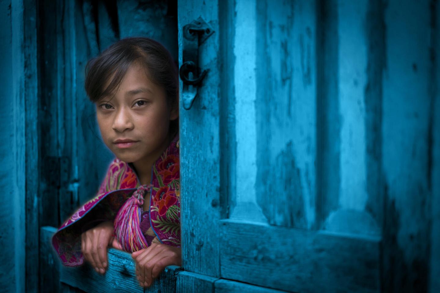 Young poor girl looking out of a window