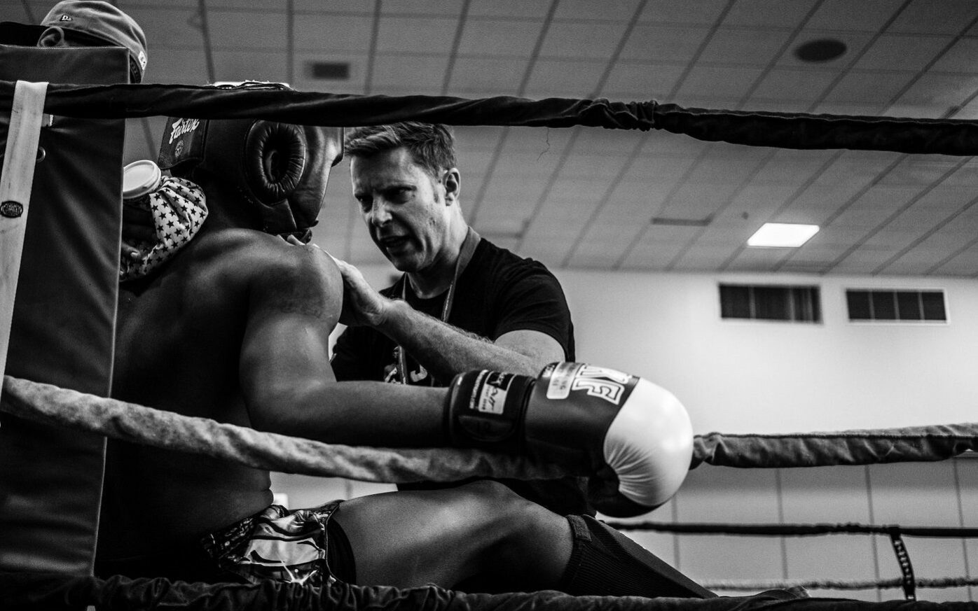 ©Wade Austin Ellis/Unsplash Photo of a boxing coaching talking to the boxer during a match